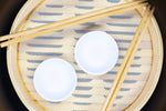 Overhead stot of bamboo steamer with chopsticks and small sushi dishes.