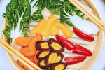 Colorful array of vegetables in bamboo tray with chopsticks on each side.